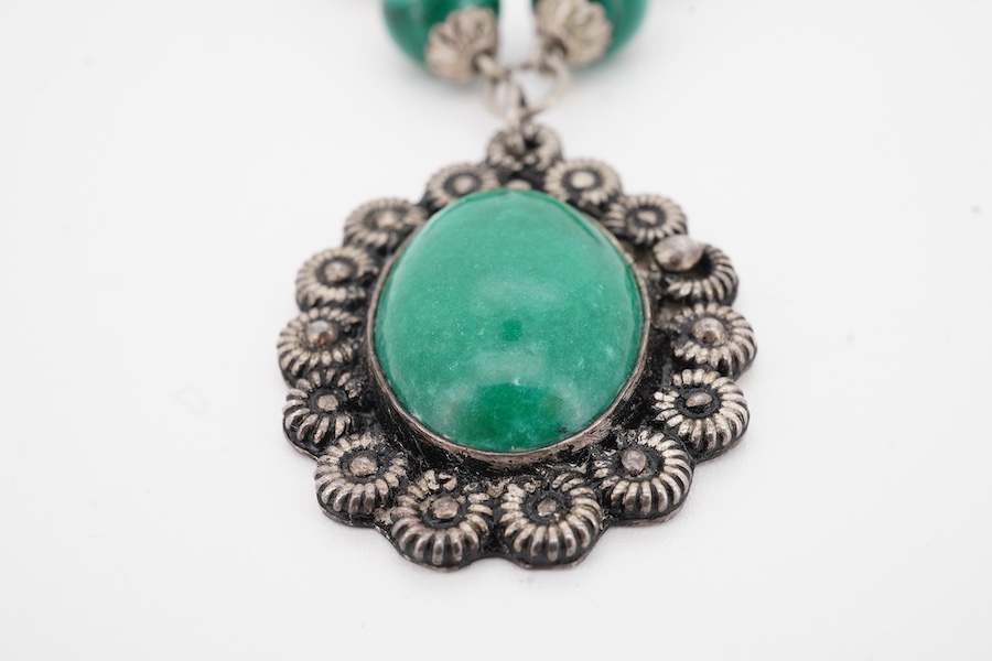 An Arts & Crafts silver and malachite necklace, early 20th century composite, the front composed of malachite beads in silver wire work mounts, suspending a green hardstone pendant in a floral silver border, necklace len